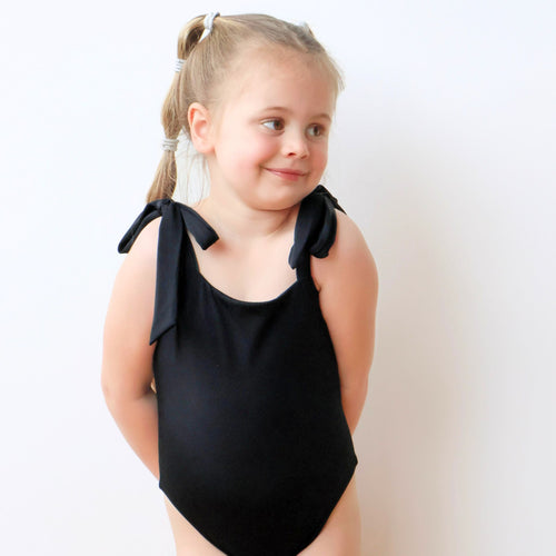 Black one-piece swimsuit for kids, front view with bowknot straps